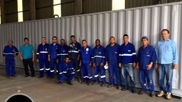 Equipe da Vetor reunida em frente a um container