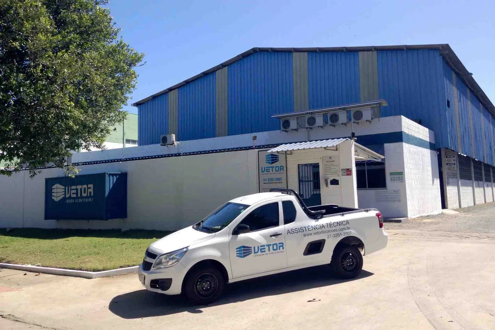 Sede da Vetor Container: galpão azul, escritório com a marca na fachada e picape da empresa